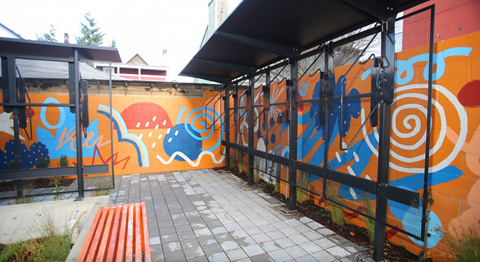 A wall with a mural of a blue elephant and a red bench.