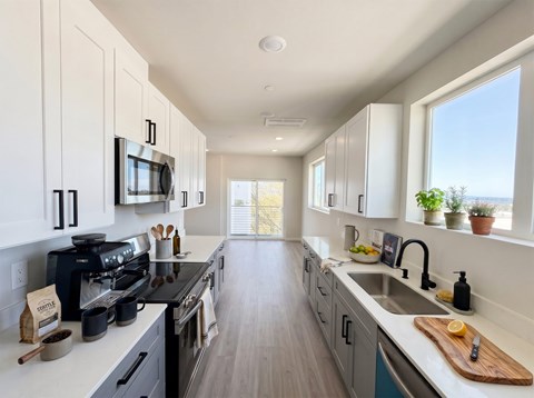 A modern kitchen with a black stove top oven and white cabinets.