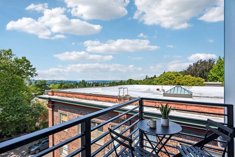 A balcony with a table and chairs overlooking a scenic view.