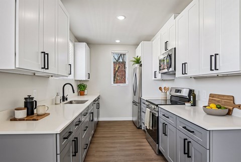 A kitchen with white cabinets and a wooden floor.