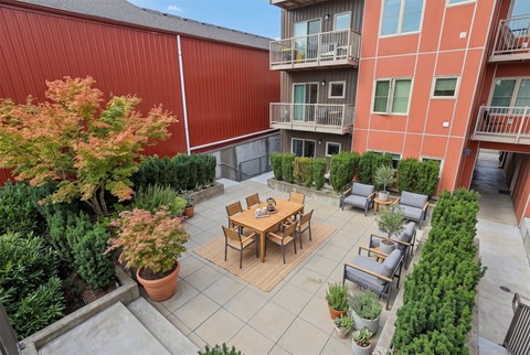A patio with a table surrounded by chairs and plants.