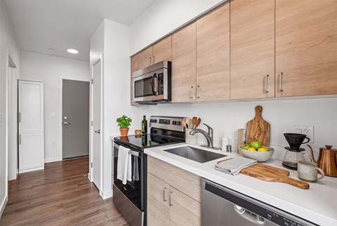 A kitchen with wooden cabinets and a black dishwasher.