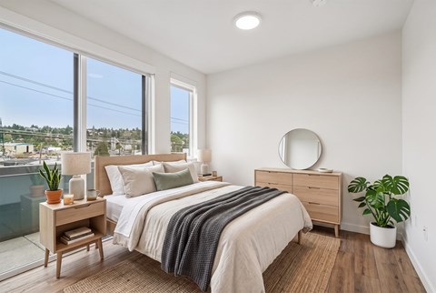 A bedroom with a large bed, a wooden nightstand, and a mirror on the wall.