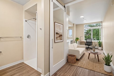 A bathroom with a white shower and a living room with a white couch.