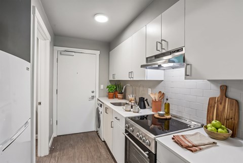 A modern kitchen with white cabinets and a stainless steel stove top.