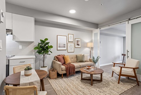 A well-lit living room with a dining table and chairs.