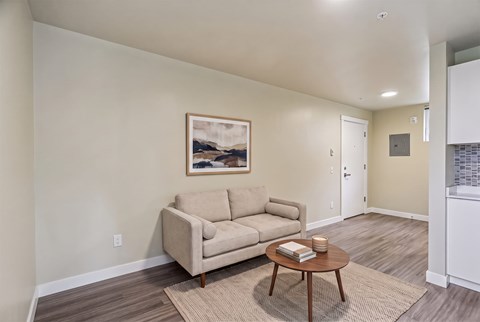 A living room with a beige couch, a coffee table, and a painting on the wall.