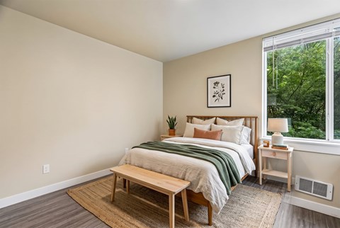 A bedroom with a bed, nightstand, and window.