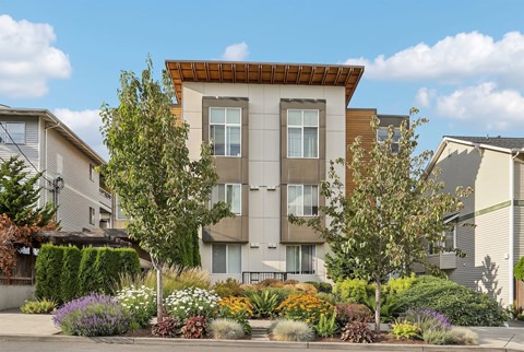 A modern apartment building with a landscaped front yard.
