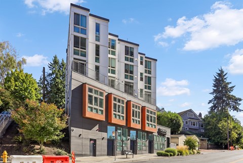 Odessa Apartments exterior under a blue sky, with orange-clad bay windows above ground-floor residential entries.