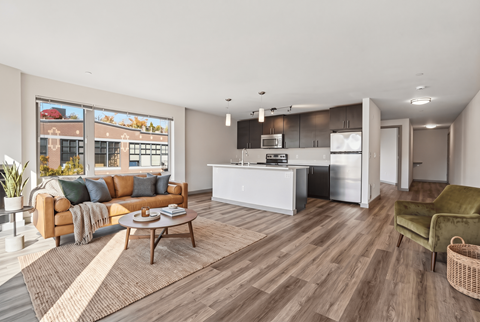 A modern living room with a kitchen in the background.