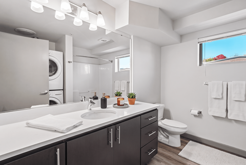 A bathroom with a white countertop and a large mirror.