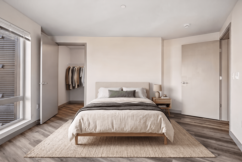 A bedroom with a large bed and a window with blinds.