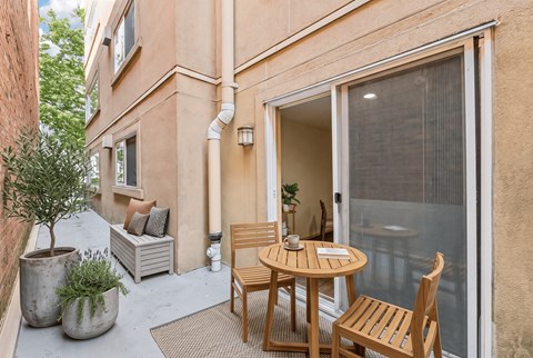 Ground-floor patio with a bistro table, a storage bench, and potted olive and lavender plants.