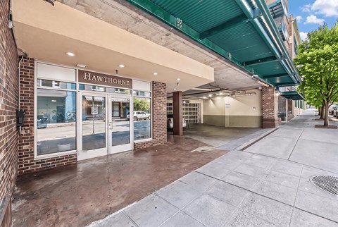 Covered entrance to Hawthorne Apartments with brick columns, beside the entrance to the parking garage.