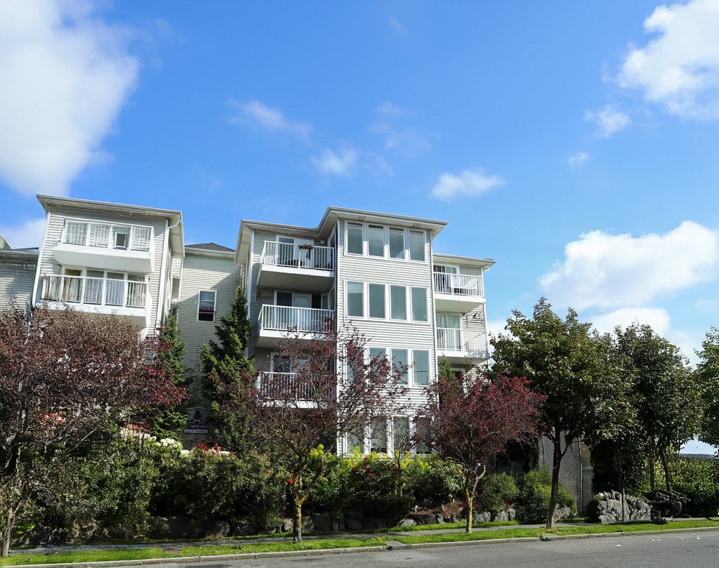 A large white apartment building with balconies and multiple windows.