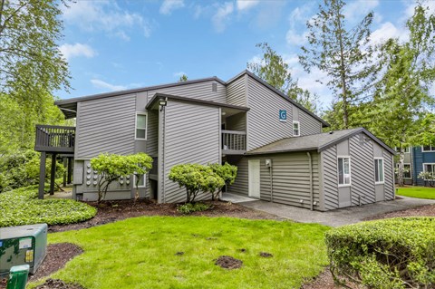 a gray house with a gray roof and gray siding with a green lawn in front of