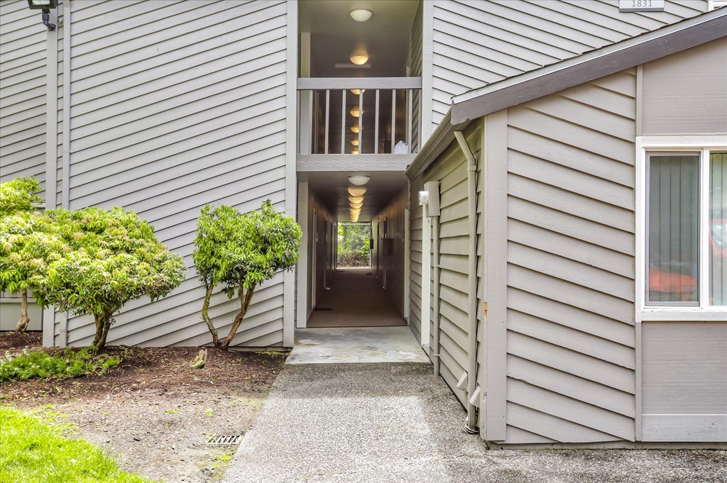 a long hallway with grey siding and a large window at the end of the hallway