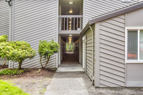 a long hallway with grey siding and a large window at the end of the hallway