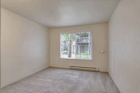 a bedroom with a large window and a carpeted floor