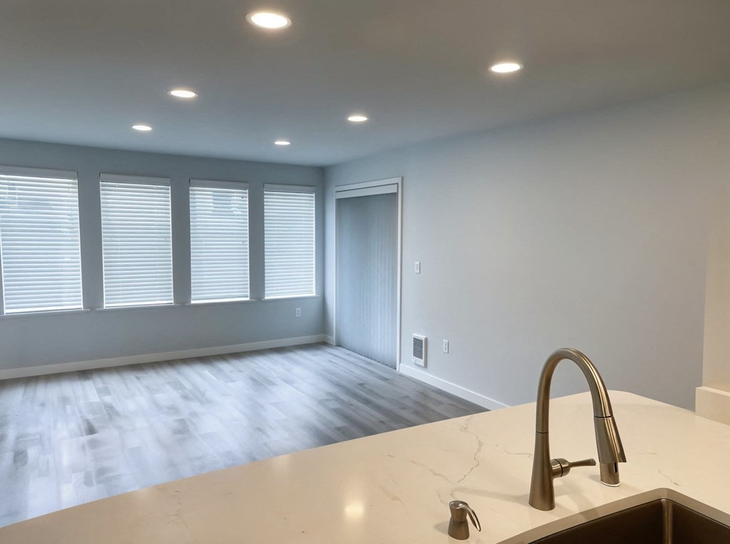 A kitchen counter with a sink and a window with blinds.