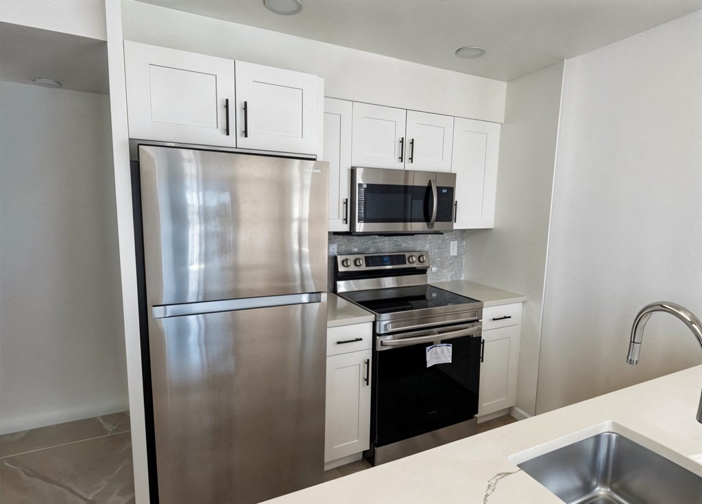 A kitchen with a stainless steel refrigerator, microwave, oven, and sink.