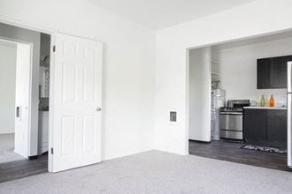 a white room with a white door and a kitchen