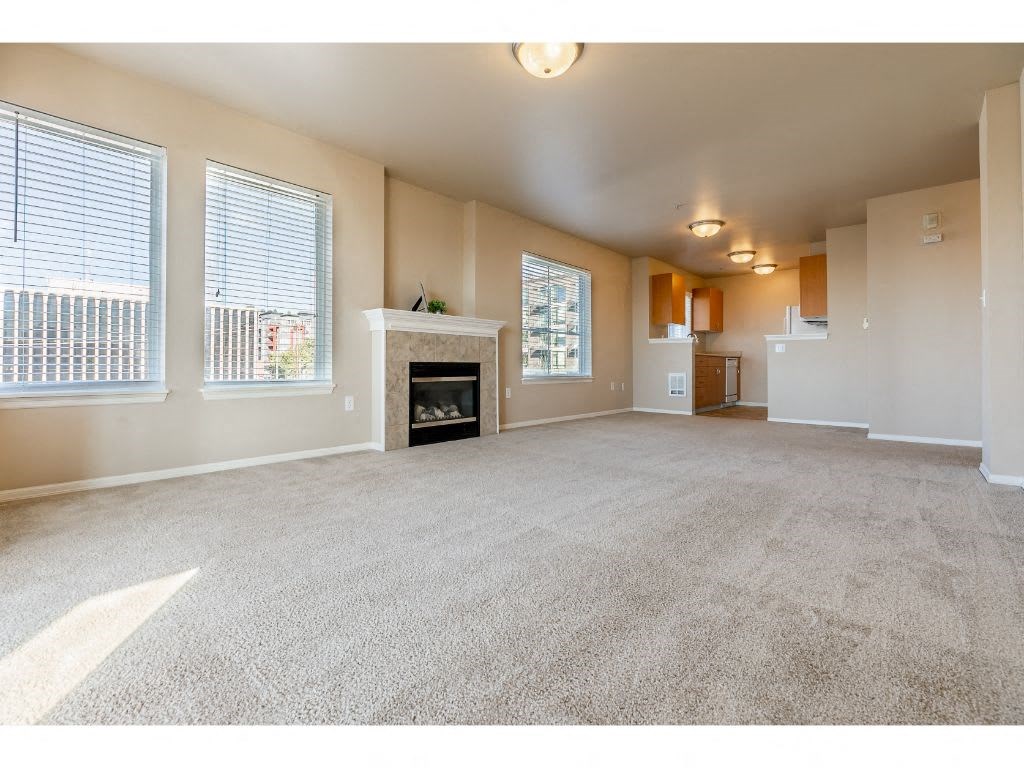 an empty living room with a fireplace and windows