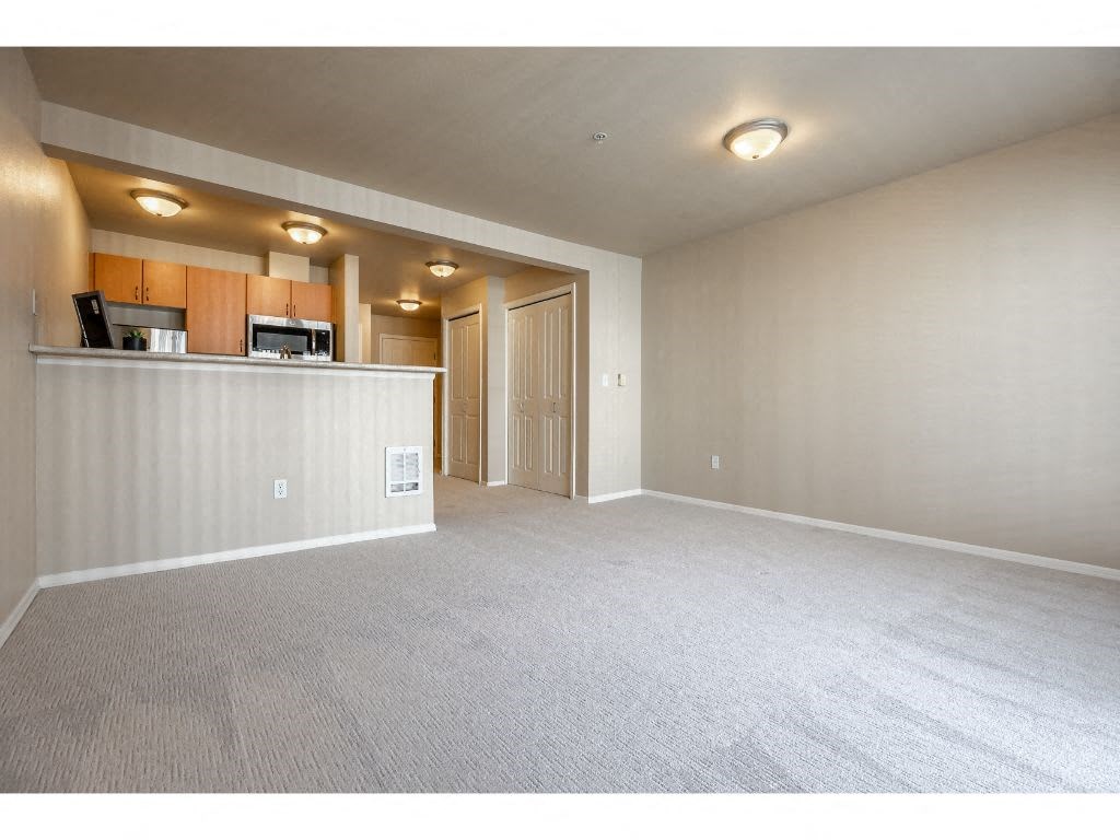 an empty living room and kitchen with a counter