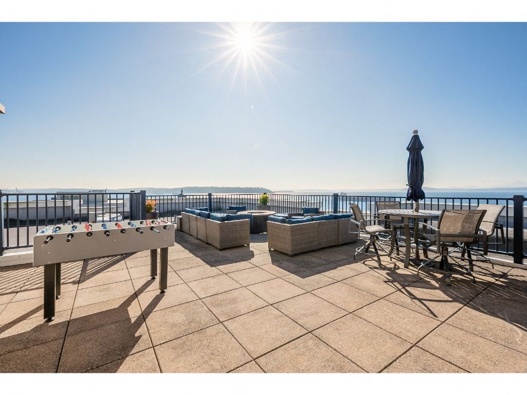 a patio with a pool table and chairs overlooking the ocean
