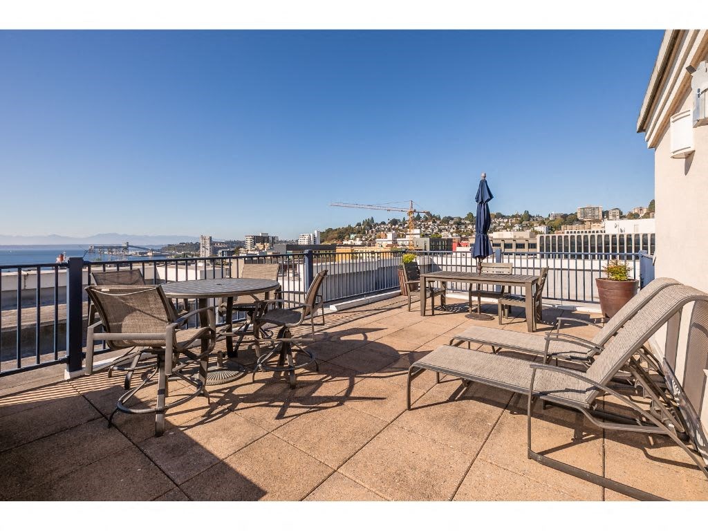 a patio with tables and chairs on a balcony overlooking the water