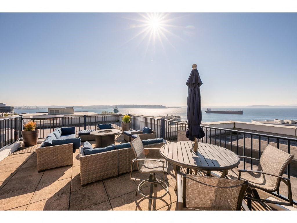 a view of the ocean from a roof deck with tables and chairs
