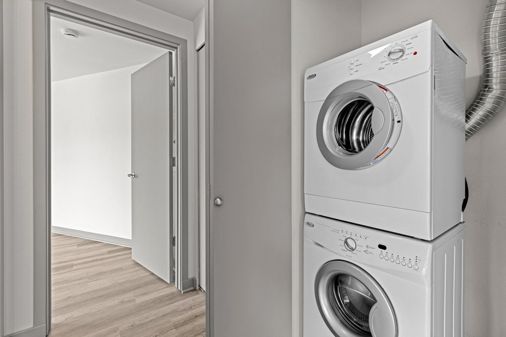 A white washing machine is stacked on top of another in a room.