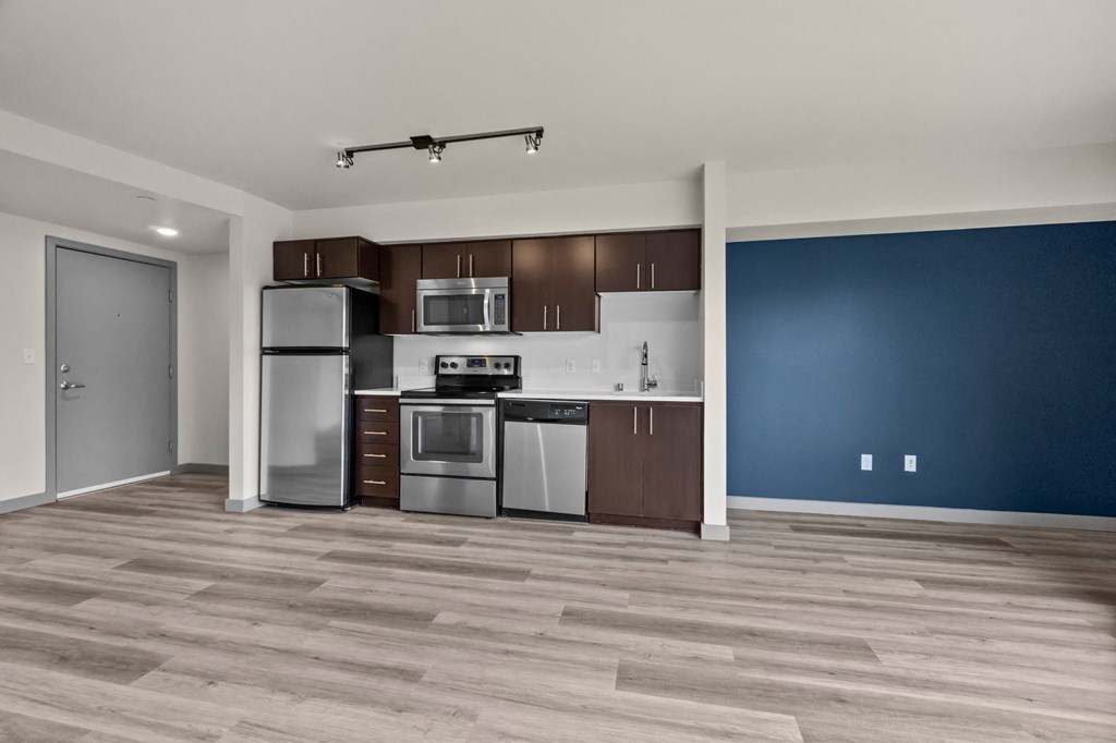 A kitchen with a blue wall and wooden floors.