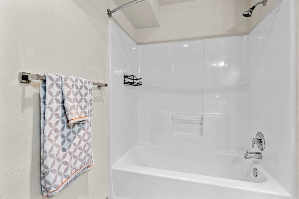 A white bathroom with a white tub and a towel hanging on the wall.