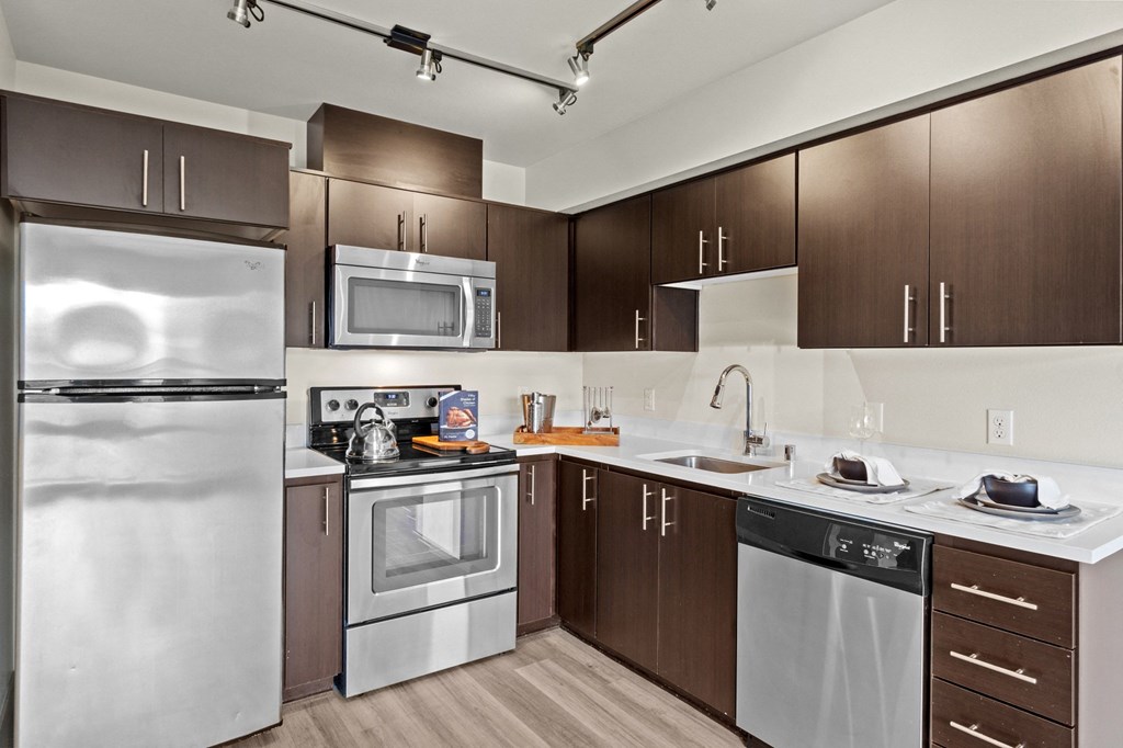 A modern kitchen with a refrigerator, oven, microwave, sink, and dishwasher.