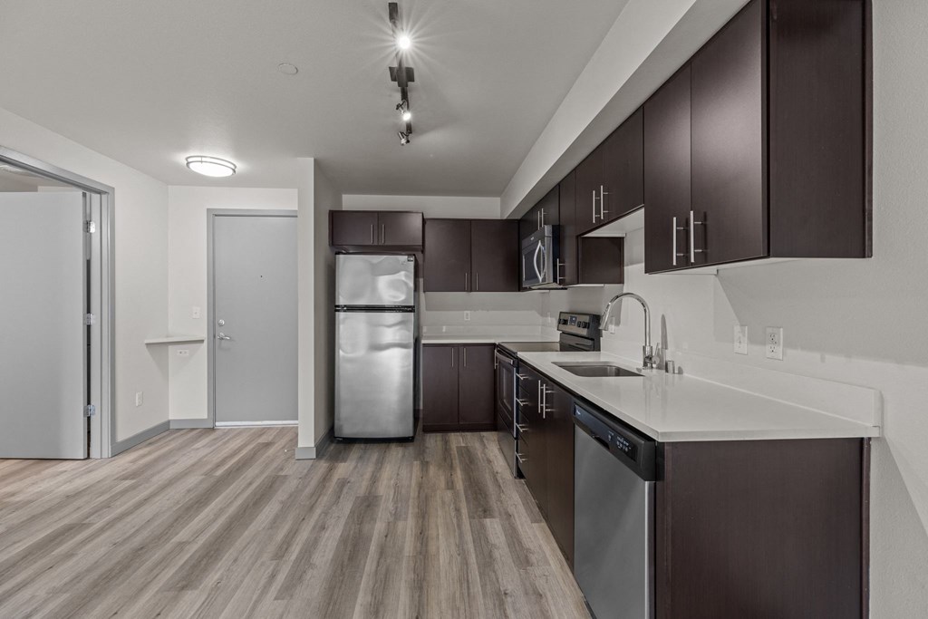 A modern kitchen with dark brown cabinets and stainless steel appliances.