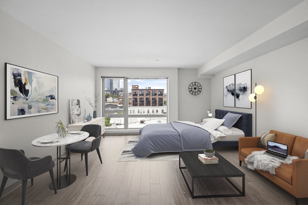 A modern bedroom with a large bed, a couch, a table, and a view of the city.