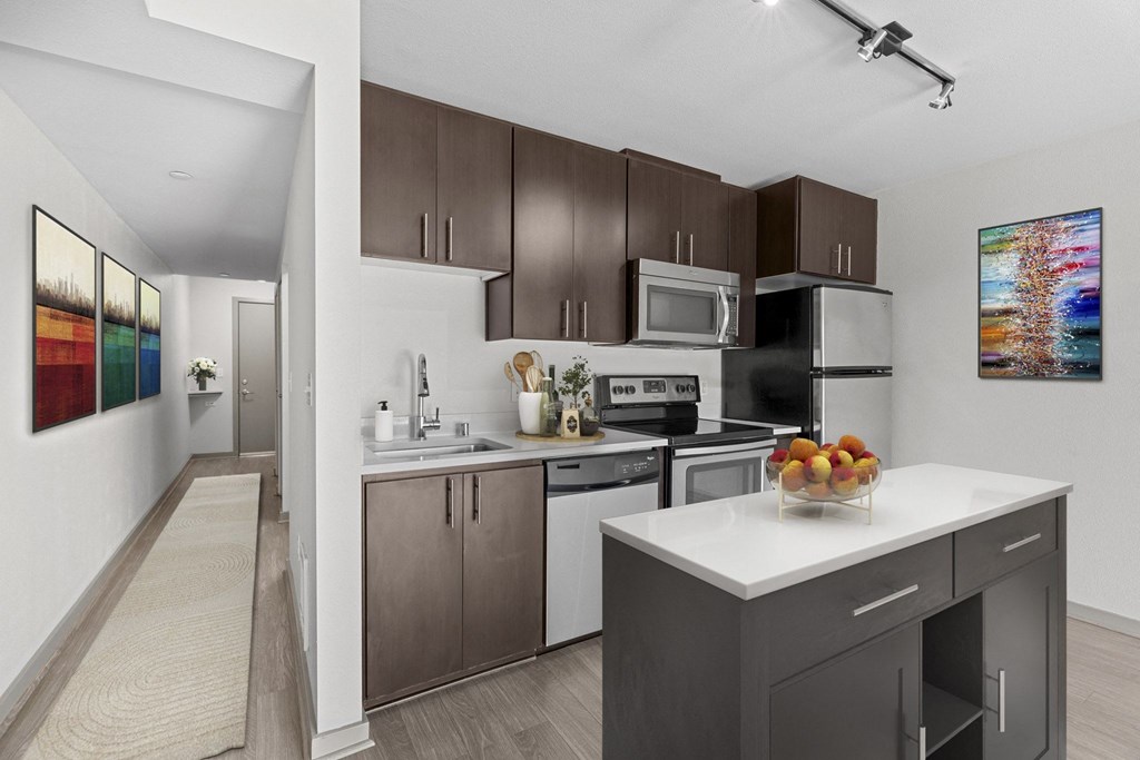A modern kitchen with a white countertop and dark brown cabinets.