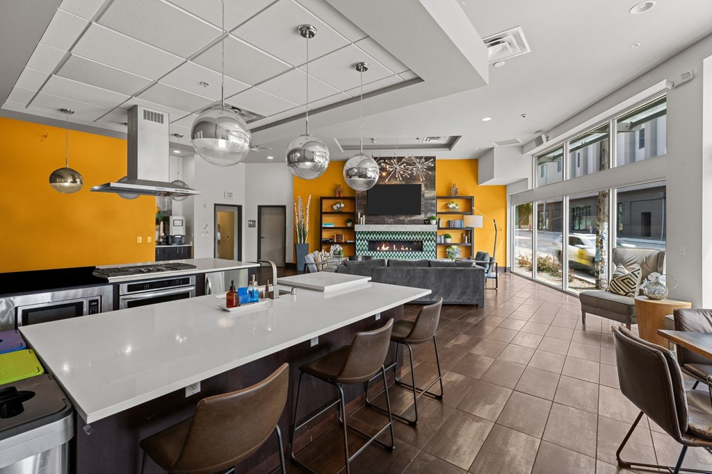 A modern kitchen with a long white island and brown chairs.