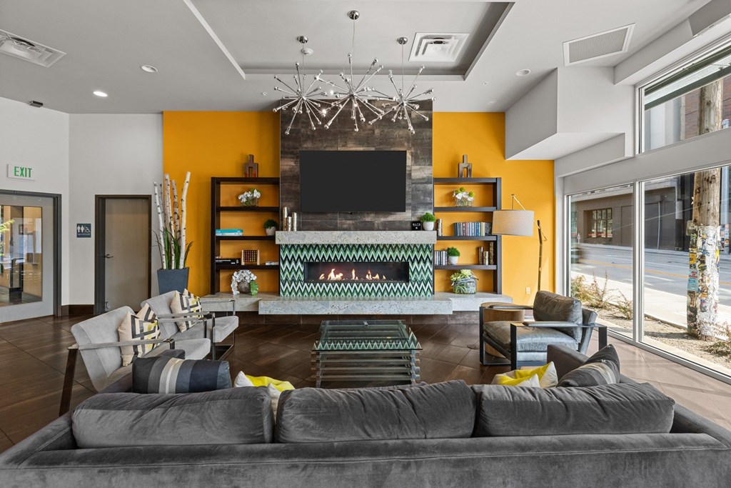 A living room with a grey sofa and a television on a yellow wall.