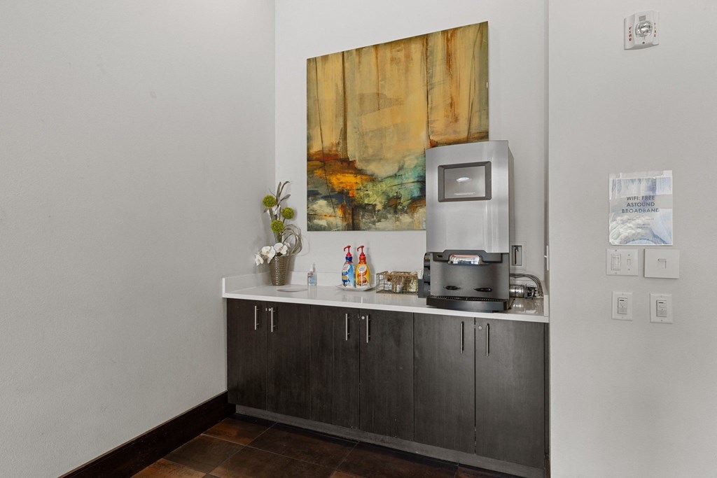 A grey counter with a vase of flowers and a coffee machine on it.