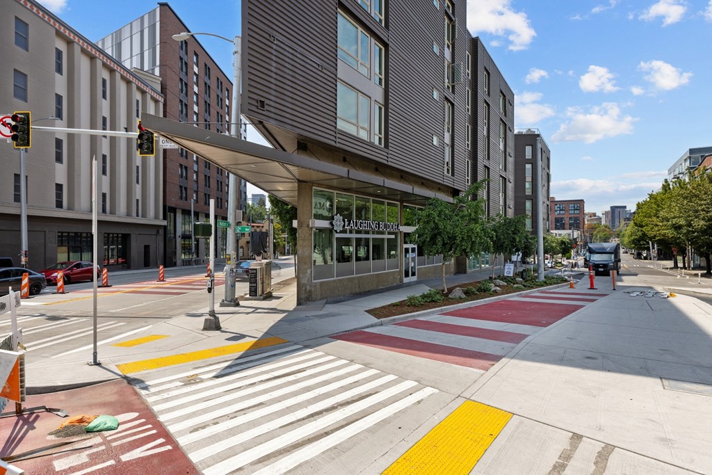 A crosswalk with red and white stripes is in front of a building with a glass facade.