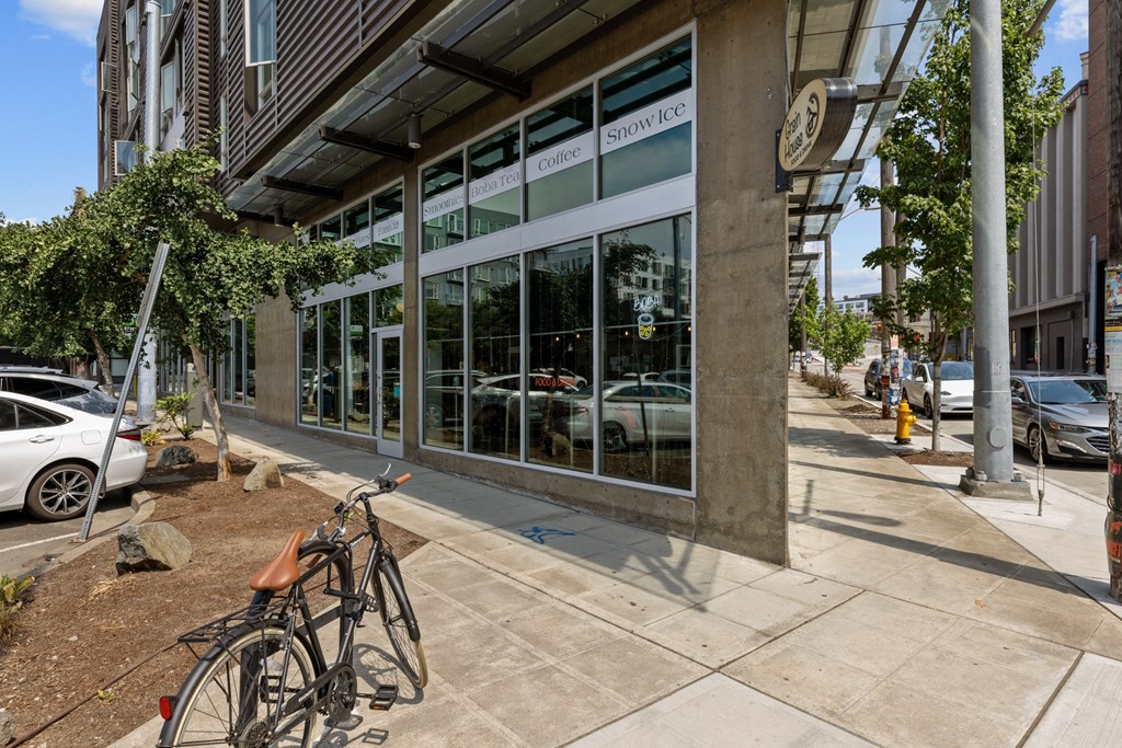 A bicycle is parked on the sidewalk in front of a building with a glass facade.