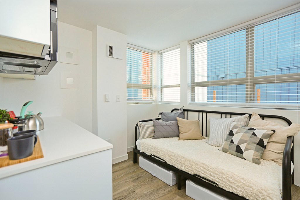 a bedroom with a bed and a kitchen with a microwave and windows