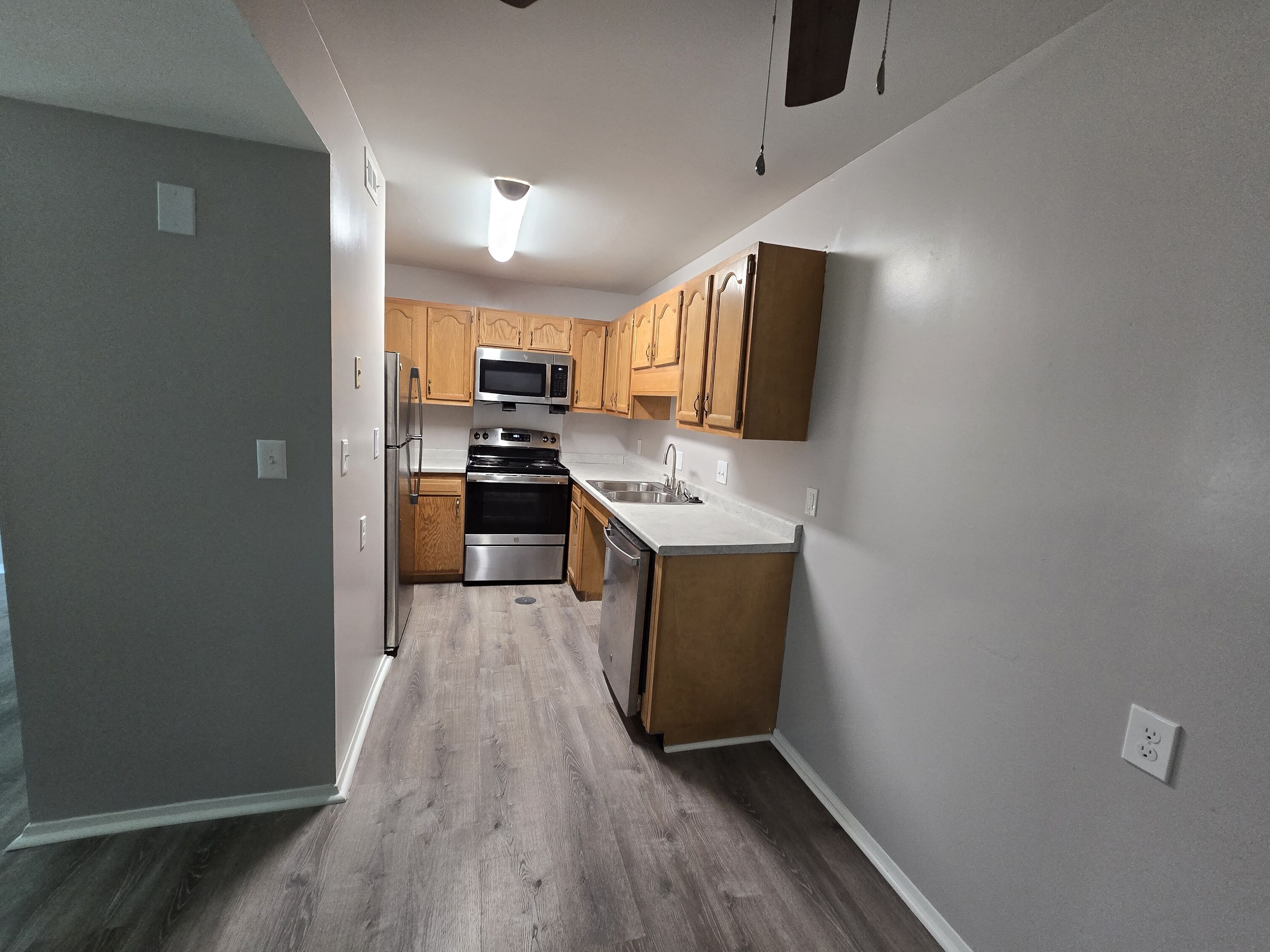 A kitchen with wooden cabinets and a stainless steel refrigerator.