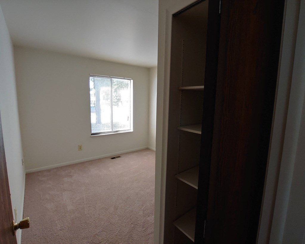 an empty room with a window and a closet