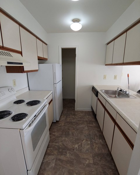 an empty kitchen with white appliances and white cabinets and a sink