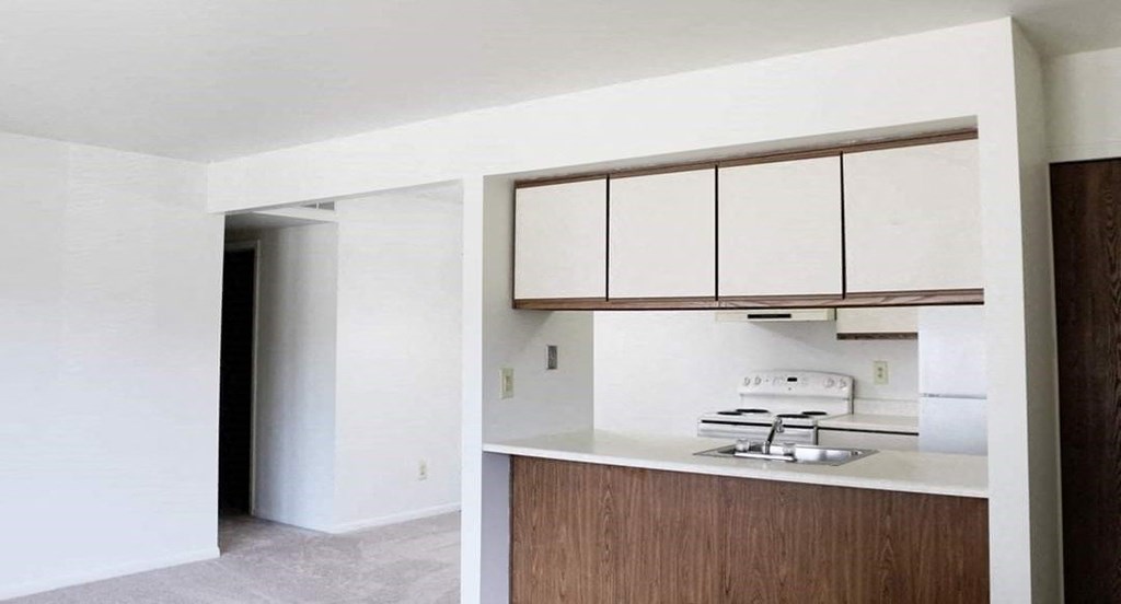 an empty kitchen with white cabinets and a sink