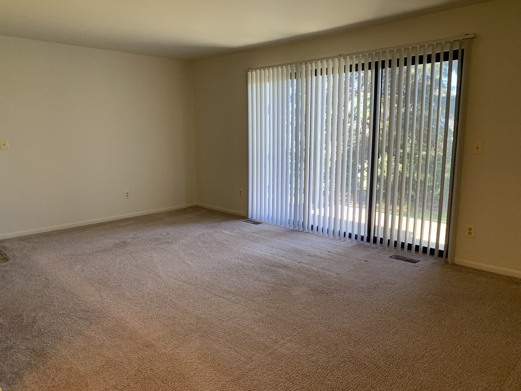 an empty living room with blinds on the window